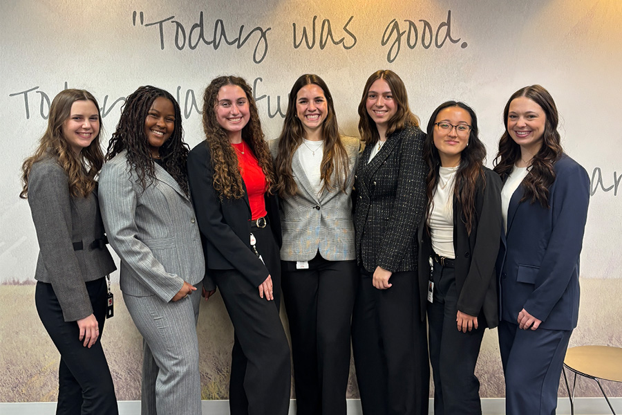 Seven women standing next to each other in front of a wall that says "Today was good."